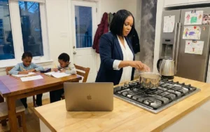 Person working on a side hustle at a kitchen table in the evening, with a laptop, paper planner and mug of tea nearby