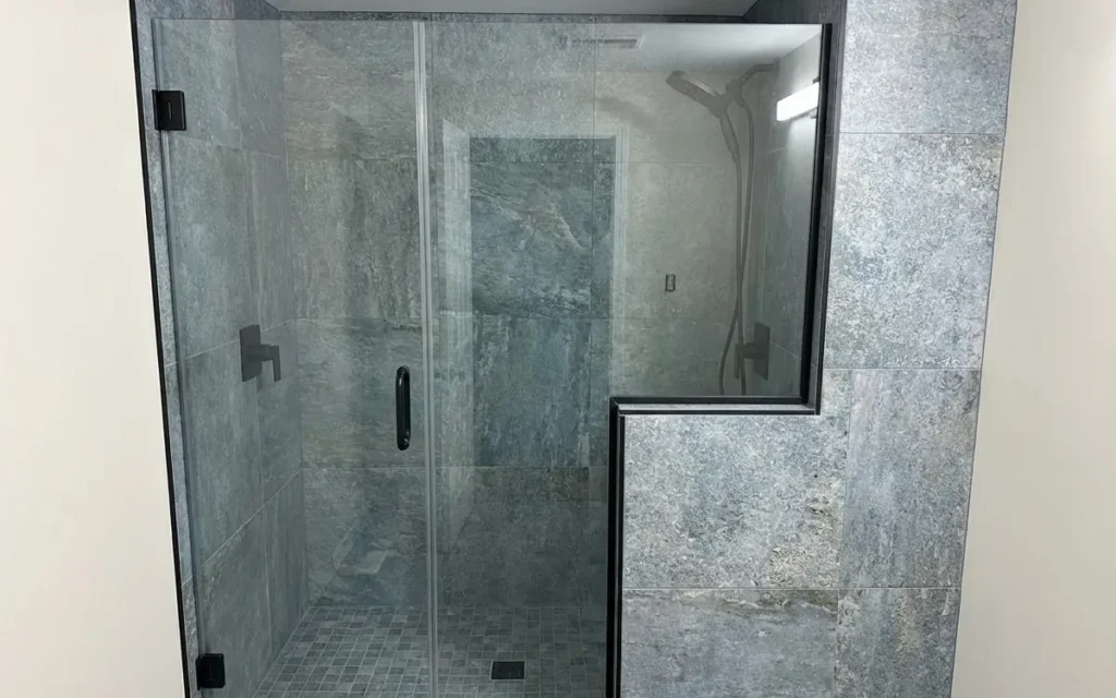 Small bathroom makeover with a frameless glass shower and grey stone tiles